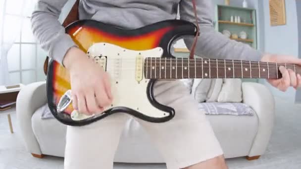 Primer plano del hombre alegre tocando una guitarra eléctrica en casa — Vídeo de stock