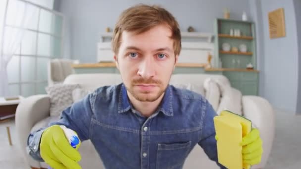 Portrait d'un homme en colère portant des gants en caoutchouc jaune tenant une éponge et pulvérisant faisant des travaux ménagers de nettoyage et de lavage — Video