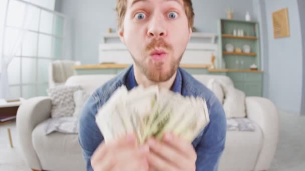 Portrait of happy successful young man holding money dollar bills in hands, slow motion. Positive emotion facial expression feeling.