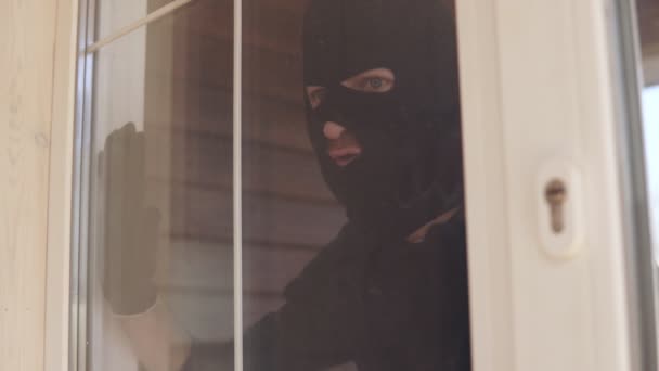 Närbild av inbrottstjuv i svart balaklava bryta sig in i ett fönster — Stockvideo