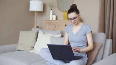 Çevrimiçi eğitim hizmetlerini kullanan gülümseyen genç bir kadın. Öğrenci dizüstü bilgisayarda eğitim kursuna bakıyor. Modern çalışma teknolojisi kavramı
