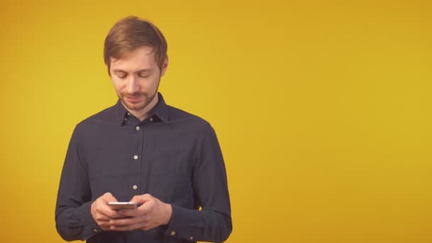Porträtt av en skakad ung man med hjälp av smarttelefon, kopiera utrymme — Stockvideo