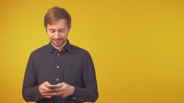 Retrato de un joven sonriente usando un teléfono inteligente, espacio para copiar — Vídeo de stock