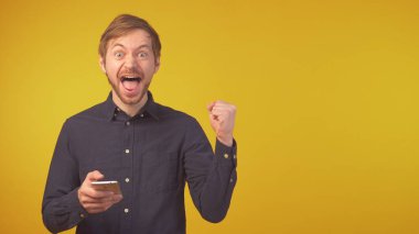 Genç adam çok mutlu ve heyecanlı. Kazanan jest yapıyor. Kolları izole edilmiş arka planda.