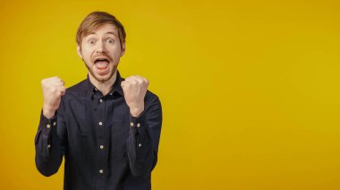 Genç adam çok mutlu ve heyecanlı. Kazanan jest yapıyor. Kolları izole edilmiş arka planda.