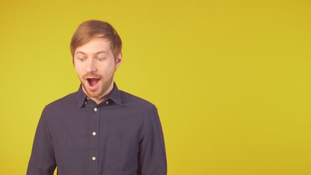 Young man in shirt holding bunch of dollar banknotes and pointing at copy space — Stock Video