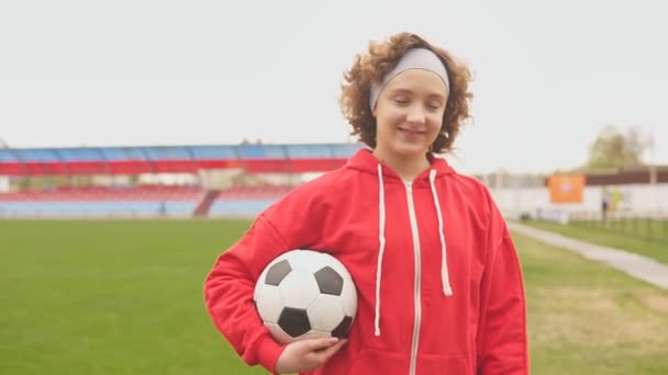 一个带着足球和慢动作的微笑的少女足球运动员的画像 — 图库视频影像