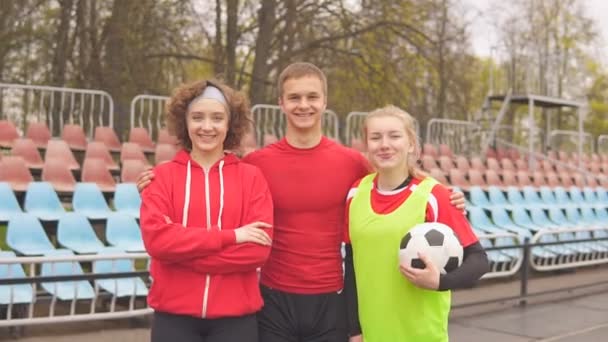 Retrato de tres amigos felices futbolistas con balones de fútbol mirando la cámara y sonriendo. — Vídeos de Stock