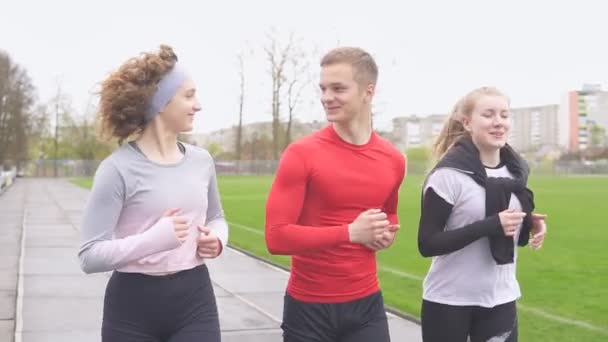Groupe d'adolescents amis sportifs courant ensemble au stade et souriant — Video