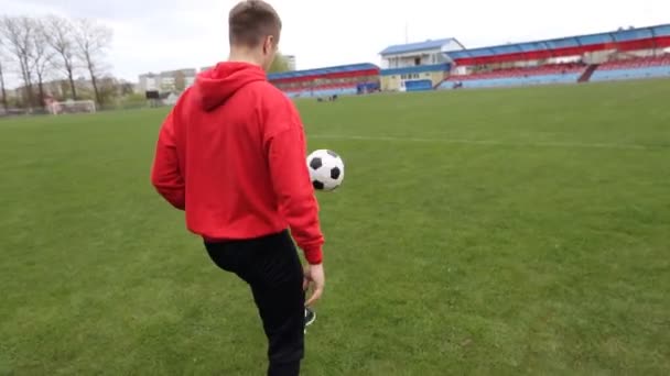 Ung tonåring fotbollsspelare jonglering fotboll på träning — Stockvideo