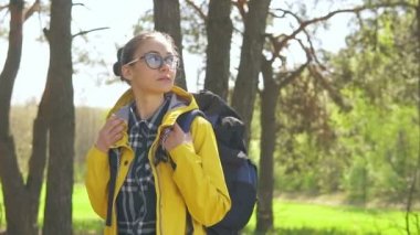 Yalnız beyaz bir kadın ormanda duruyor ve etrafındaki güzel odunlara bakıyor - vahşi doğada alternatif yürüyüş tatili kavramı - sırt çantalı ve gezgin insanlar