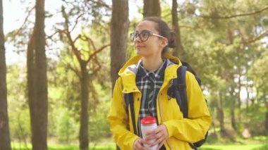Vahşi ormanda termosla yürüyen genç bir kadın turist. Seyahat ve yürüyüş konsepti