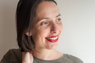 Evdeki genç doğal kadın, huzurlu bir ifadeyle pencereye bakıyor.