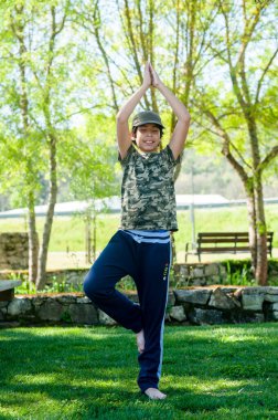 Güneşli bir günde parkta yoga yapan tatlı bir çocuk..