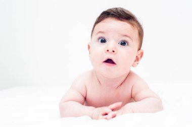 Beyaz arka planda yatağında karnının üstünde yatan tatlı bir bebek. Büyük kopyalama alanı olan resim.