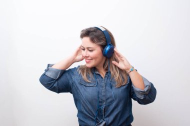 Mutlu sarışın kadın, elleri kulaklıkla beyaz arka planda müzik dinliyor. Harika kopyalama alanı.