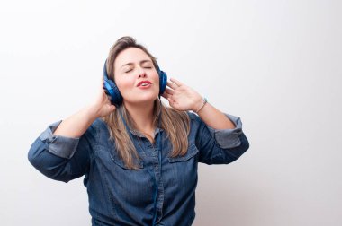 Mutlu sarışın kadın, elleri kulaklıkla beyaz arka planda müzik dinliyor. Harika kopyalama alanı.