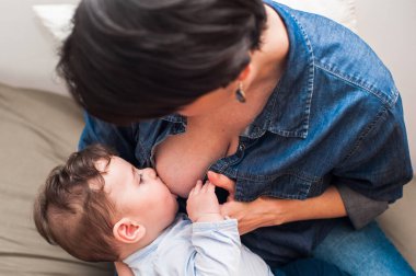 Günlük rutin. Bir annenin bebeğini kucağına alıp emzirmesinin yüksek açılı görüntüsü.