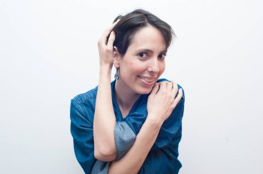 Kot pantolonlu, gülümseyen ve kendini tutan kameraya bakan doğal bir kadın..