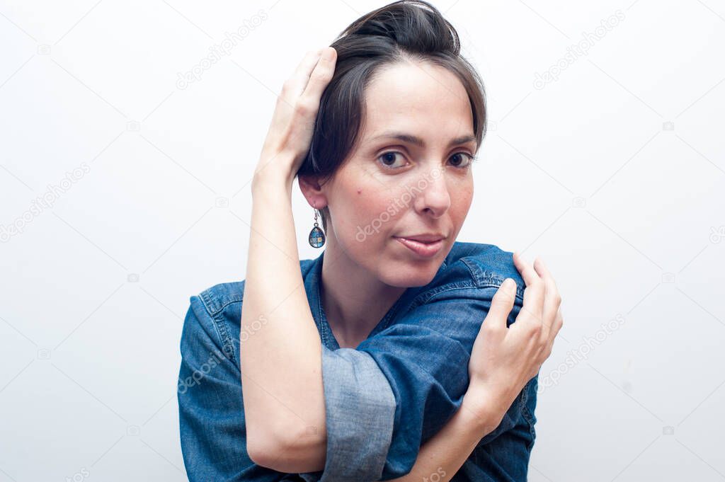 natural beautiful woman in blue jeans looking at the camera holding herself.