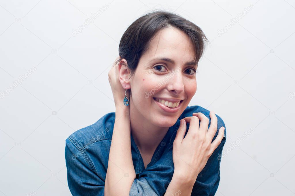 natural beautiful woman in blue jeans smiling and looking at the camera holding herself.