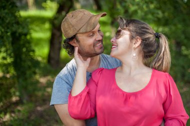 Mutlu çift birbirine romantik bir şekilde bakıyor. Onun yanağını usulca tutuyor..