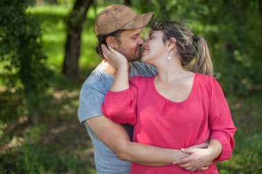 Mutlu çift birbirine sarılıyor ve parkta usulca öpüşüyor.