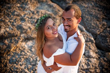 Gelin ve damadın kameraya sarılmış yüksek açılı görüntüsü.