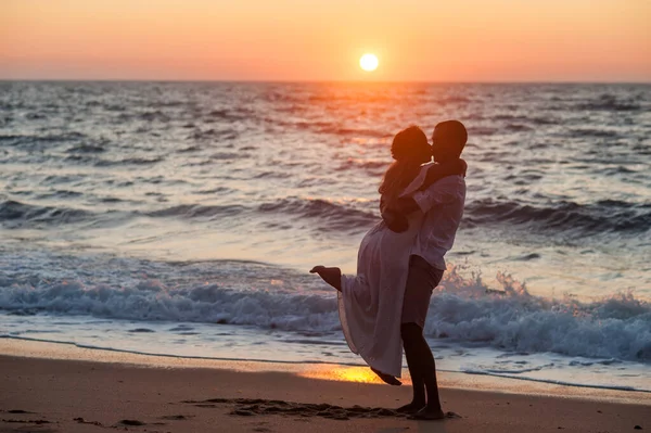 新郎は空気中で彼の最愛の抱擁し ビーチで日没時に彼女の口にキス — ストック写真