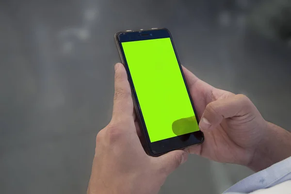Mobile on hands with green screen.