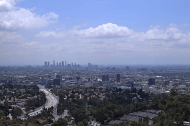 Otoyol trafiği ve bulutlu gökyüzü ile Los Angeles silüeti.