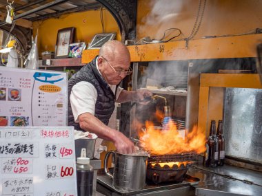 Toyo-san, Osaka 'daki Izakaya Toyo' nun sahibi. 17 Ocak 2020 'de Osaka, Japonya' da yemek pişirmek için alev püskürtücü meşalesiyle sadece çıplak elini kullanır.