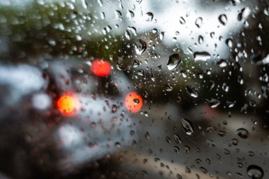 Arka planda bulanık ve nemli sokak trafiği olan ön camda yağmur damlası, Bangkok, Tayland, Haziran 2018.