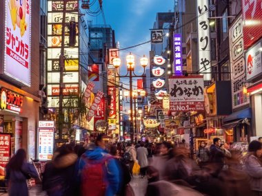 Akşam Dotonbori caddesinde yemek bulmak için gezen birçok turistin uzun pozlu görüntüsü var. Osaka, Japonya, Ocak 2020 tabelasında birçok dükkanın adı geçiyor.