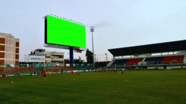 Futbol takımının akşamdan akşama kadar stadyumda krom anahtar için yeşil ekranla antrenman yaptığı, antrenman bittiğinde stadyumun ışığının açılıp kapandığı zaman: Bangkok, Tayland, Temmuz 2013