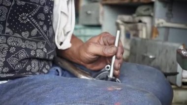 Tamirci çekiçle metal parçalarına vuruyor. El kameralı yavaş çekim, 29.97fps.