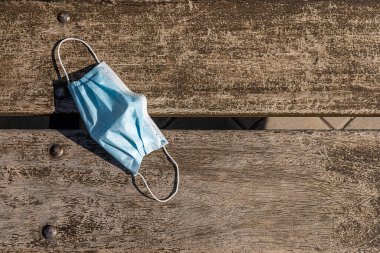 Ahşap bir bankta mavi koruyucu maske.