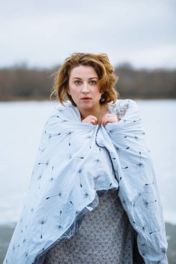 Şaşırmış bir kız, battaniyeye sarılmış.