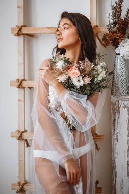 Doğulu bir gelin iç çamaşırlarıyla merdivenlerin yanında duruyor.