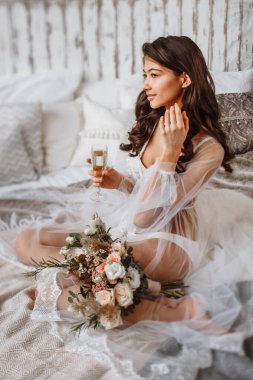Gelin iç çamaşırlarıyla yatağında bir bardak şampanyayla