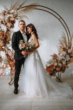 Düğün kemerinin arkasında bir buket ve damat olan gelin.