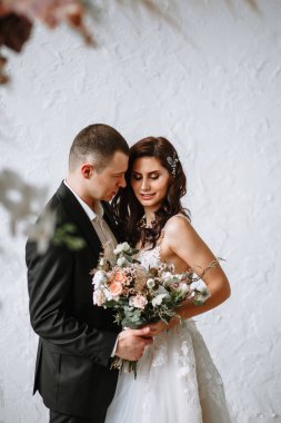 Düğün kemerinin arkasında bir buket ve damat olan gelin.