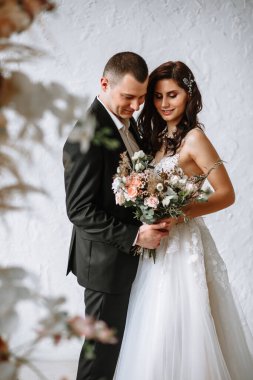 Düğün kemerinin arkasında bir buket ve damat olan gelin.