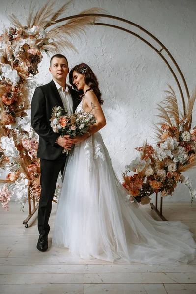 結婚式のアーチの背景に花束と新郎と花嫁 — ストック写真