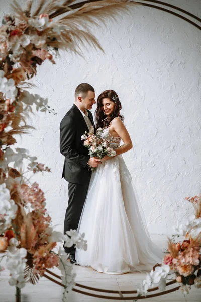 結婚式のアーチの背景に花束と新郎と花嫁 — ストック写真