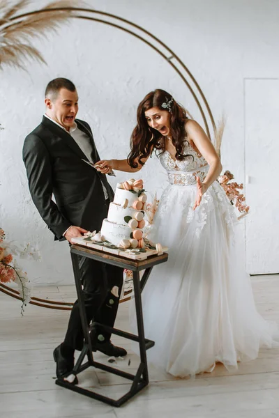 Drie lagen bruidstaart vallen van de tafel. Emoties van de bruid en bruidegom als de taart valt — Stockfoto