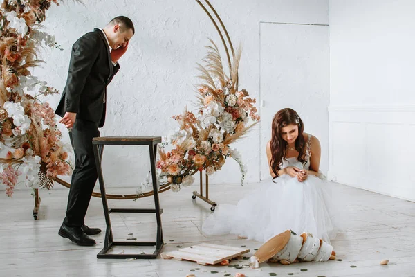 Háromszintes esküvői torta hullik le az asztalról. Érzelmek a menyasszony és a vőlegény, amikor a torta esik — Stock Fotó
