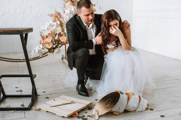 Three-tiered wedding cake falling from the table. Emotions of the bride and groom when the cake falls — Stock Photo, Image