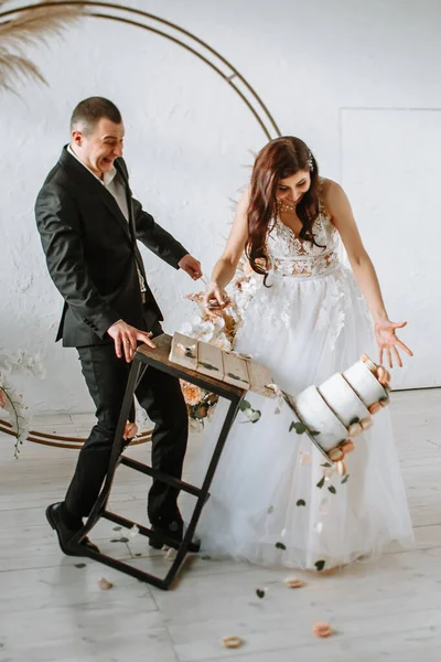 Drie lagen bruidstaart vallen van de tafel. Emoties van de bruid en bruidegom als de taart valt — Stockfoto