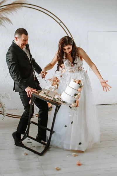 Трехъярусный свадебный торт падает со стола. Эмоции жениха и невесты, когда торт падает — стоковое фото